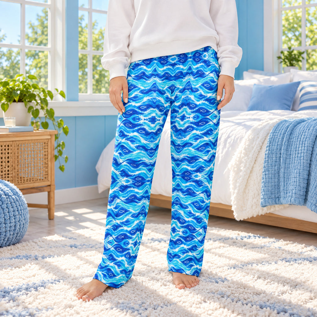 Lifestyle photo: Living Water Waves faith-based all-over-print pajama pants in a cozy bedroom setting.